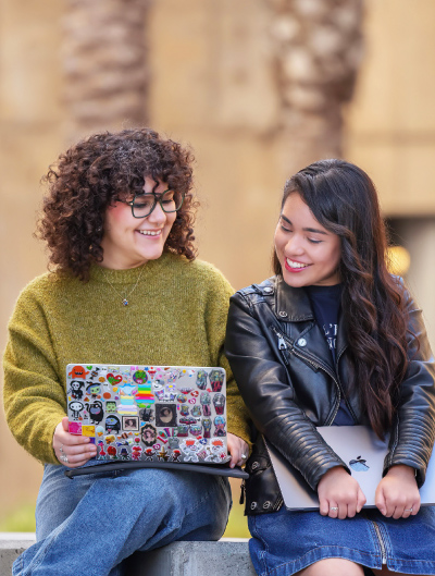 Two students looking at computer outside